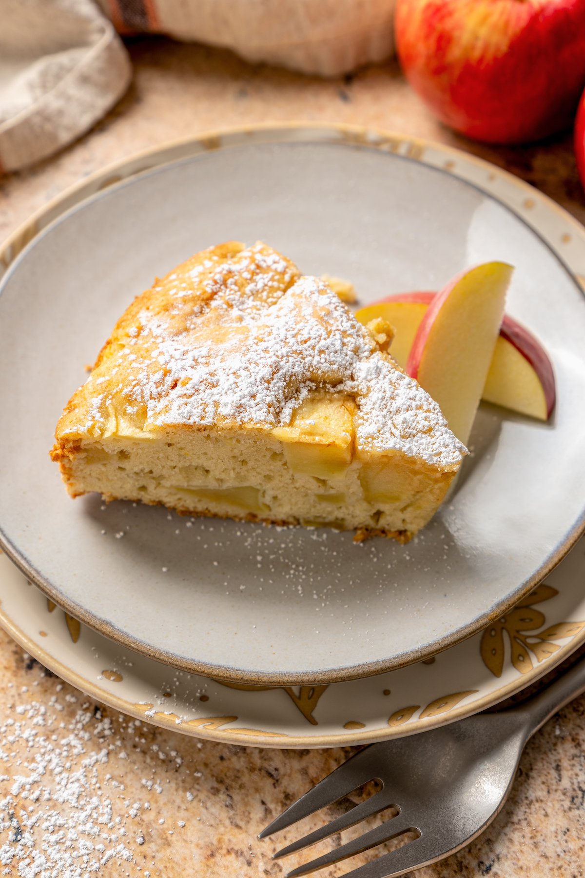 Close-up of a slice of fluffy apple cake with powdered sugar. 