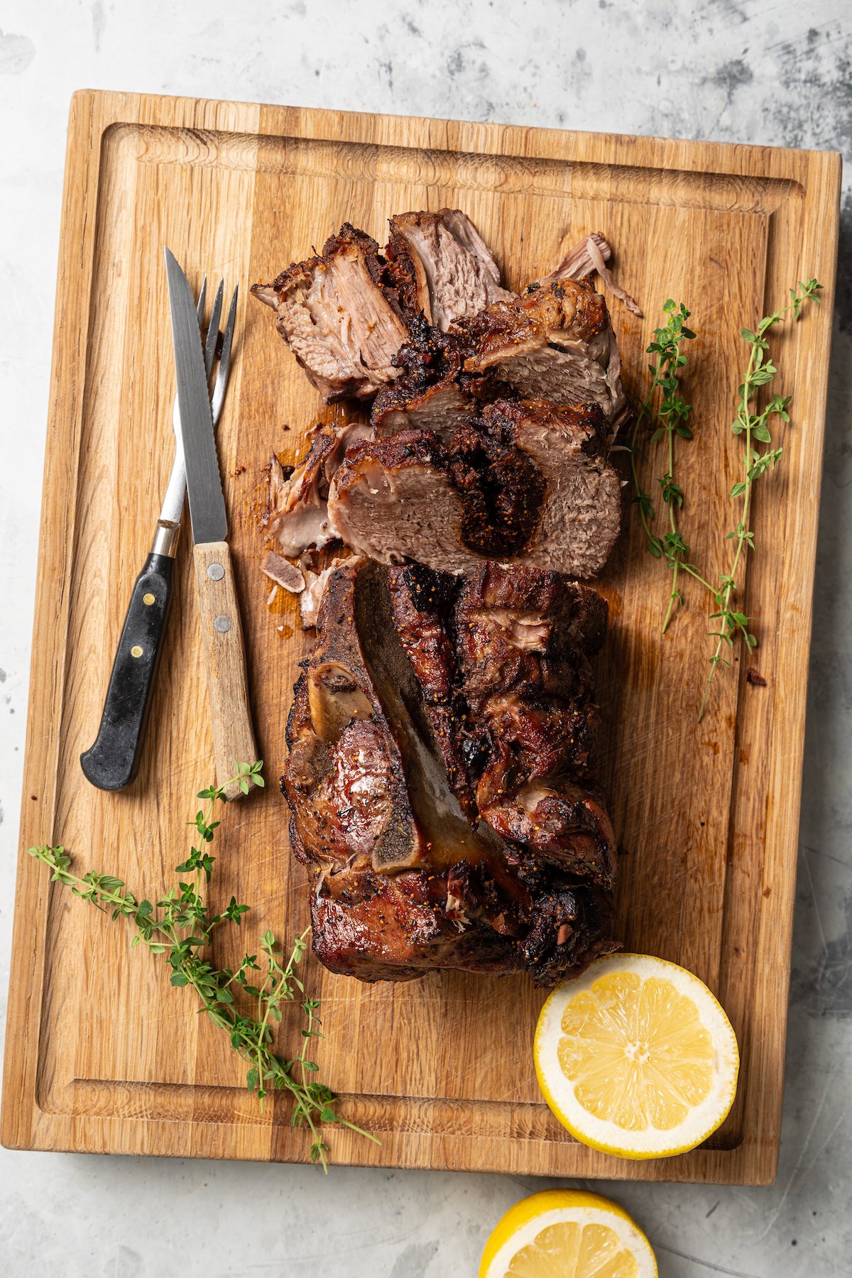 Slicing into the juicy, roasted pork shoulder on a cutting board. 