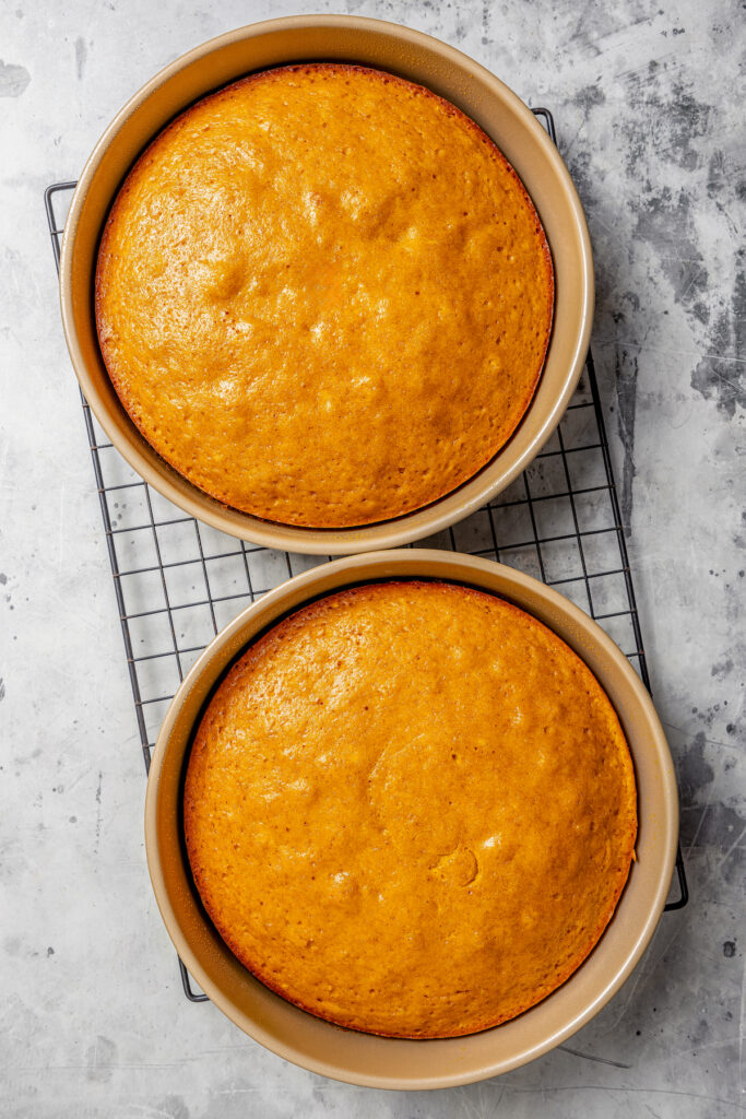 Baked cakes in springform pans over a wire rack for cooling. 